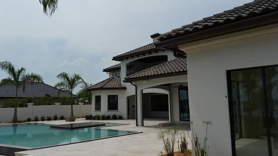 White stucco two story home barrel tile roof bronze half round gutter pool, Lake